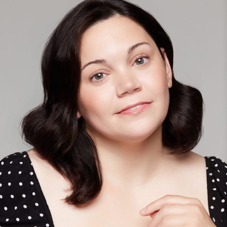 Portrait of a woman with shoulder-length dark hair, wearing a polka dot dress.